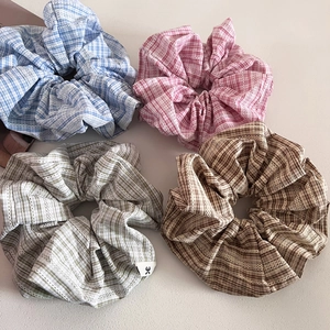 Close-up of four plaid fabric scrunchies with delicate lace edges in pastel colors