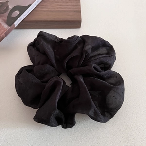 Detailed view of large black polka dot scrunchie with soft ruffled tulle fabric texture