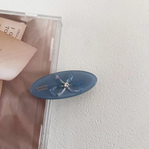 Close-up of blue oval acetate hair clip with bow rhinestone and golden handmade text
