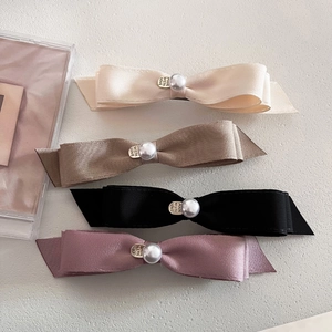 Detailed view of four satin bows with central pearls and engraved metal love charms