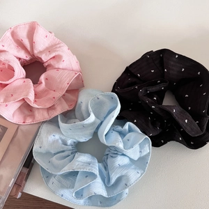 Detailed view of layered heart print scrunchies in soft pink, blue, and black fabric