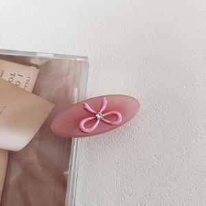 Detail of pink acetate oval clip with rhinestone bow and France Handmade gold logo