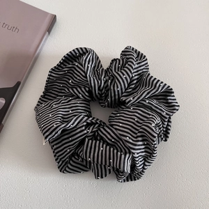 Close-up of black and white striped hair scrunchie with silver polka dots and pleated texture
