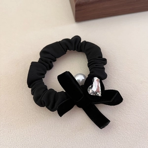 Chouchou élégant en velours avec nœud, strass en cœur et perle sur surface premium