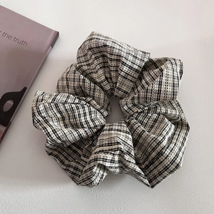 Detail showing oversized plaid scrunchie with white lace trim and cotton linen texture