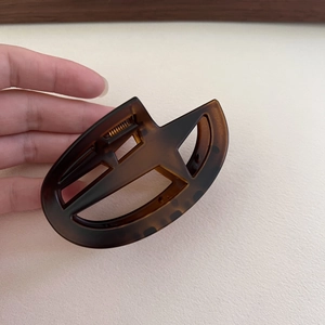 Detail of dark brown tortoiseshell star hair claw clip held by hand for size scale