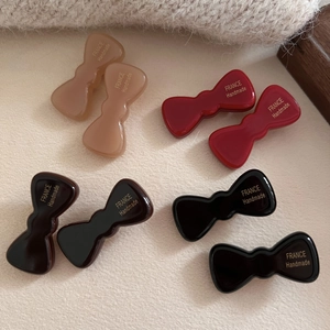 French vintage acetate bow hair clips in red and champagne displayed on beige fabric