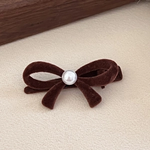 Detailed shot of brown velvet bow hair clip with a central pearl and alligator clip base