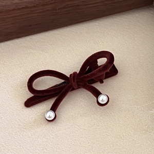 Detailed close-up of red velvet bow hair clip with elegant white pearl accents