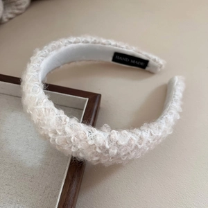 Fuzzy white faux lambswool wide headband with handmade label on minimalist wood tray