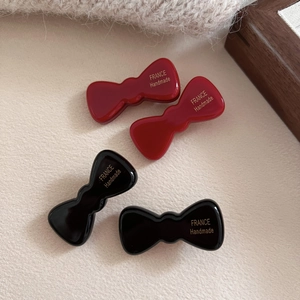 Detail of red and black acetate bow hair clips with gold France Handmade logo