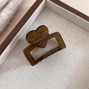 Detail of an amber heart-shaped acetate hair claw clip on a rustic display tray
