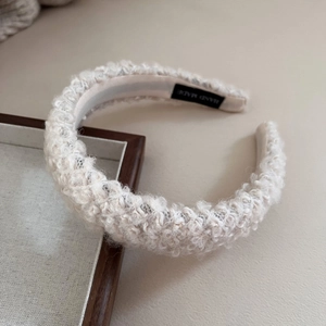 Detail of soft cream boucle lamb wool headband with handmade label and fuzzy texture