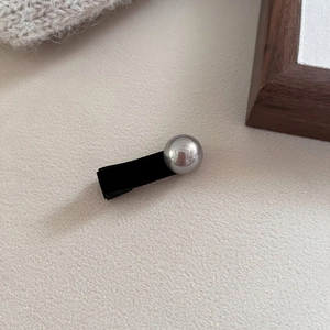 Detail view of a black velvet duckbill hair clip with a polished silver metallic sphere