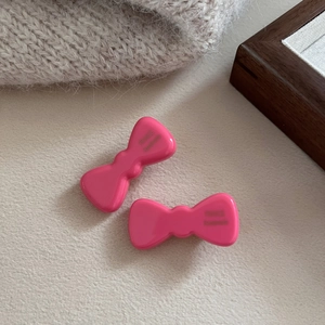 Close-up of two pink acetate bow hair clips with France Handmade text on light fabric