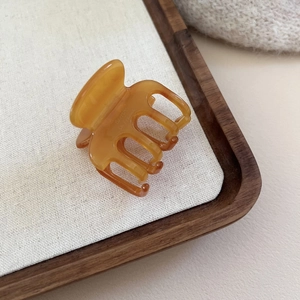 Pince à cheveux élégante en acétate écaille ambre sur fond esthétique en lin blanc neutre