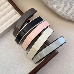 Close-up of five minimalist acetate hair clips in neutral colors on a display box