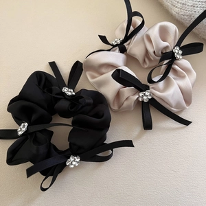 Détail de chouchous en satin de soie noir et champagne avec strass et nœuds décoratifs