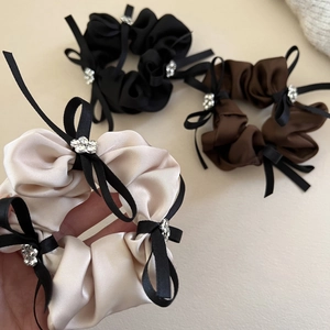 Gros plan de chouchous en satin avec nœuds noirs et fleurs en strass en divers coloris