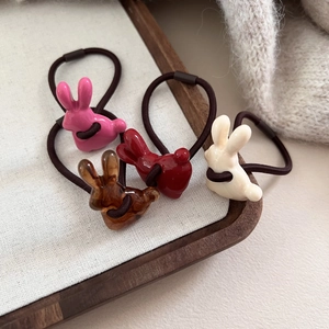 Élastiques à cheveux lapin mignon en quatre couleurs sur plateau bois et fond tricot