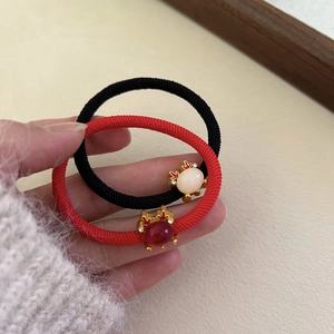 Elastic red hair tie featuring a golden crab charm with a deep red gemstone center