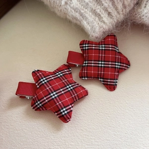 Pair of festive red and black plaid star hair clips with soft fabric texture