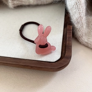 Détail d'un élastique cheveux lapin en résine rose sur un fond en maille douce