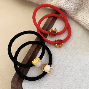 Close-up of four red and black elastic hair ties with festive golden metal charms