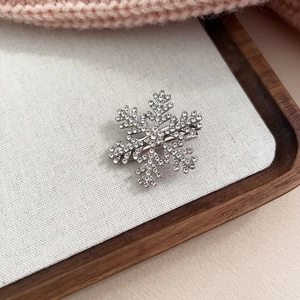 Vue détaillée d'une barrette flocon avec strass sur lin blanc et pull d'hiver chaud