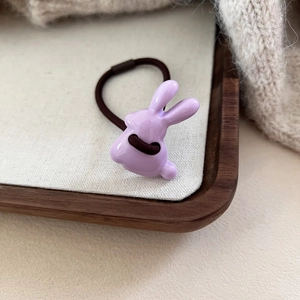 Gros plan d'un chouchou lapin en résine violette sur un fond décoratif en tissu doux