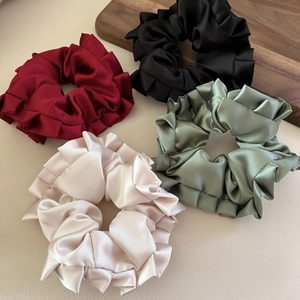 Large satin silk scrunchies in wine red, black, green and beige colors on wooden tray