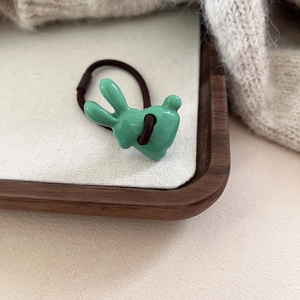 Détail de l'élastique lapin vert sur plateau en bois avec maille de pull chaleureuse