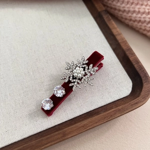 Détail de la pince à cheveux flocon en velours rouge avec perles et strass brillants