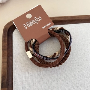 Dettaglio macro degli elastici per capelli marroni minimalisti con accenti dorati e quadri