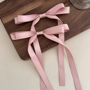 Pink satin bow hair clips featuring long ribbons for elegant half-up hairstyles
