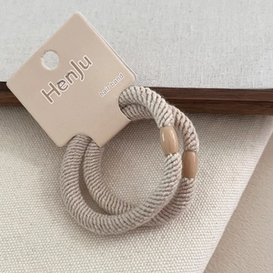 Detailed close-up of beige twill elastic hair bands with smooth plastic buckle fasteners