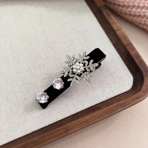 Détail de la pince à cheveux flocon en velours avec perles et strass scintillants