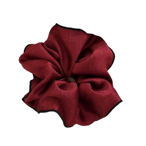 Elegant satin scrunchie in deep wine red with black contrast piping for a stylish ponytail