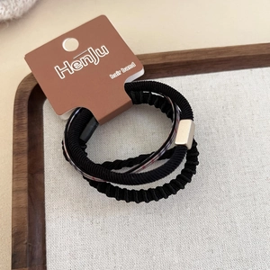Dettaglio di elastici per capelli neri con fibbia in metallo dorato su vassoio di legno