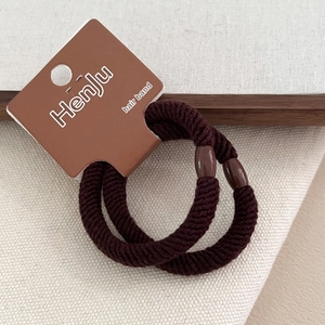 Close-up of thick coffee brown hair ties with twill weave texture and plastic buckle