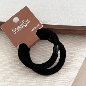 Close-up of black elastic hair bands with secure oval bead on branded display card