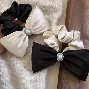 Detail von Satin-Haarschleifen mit Perlen und Strasssteinen in Schwarz und Champagner