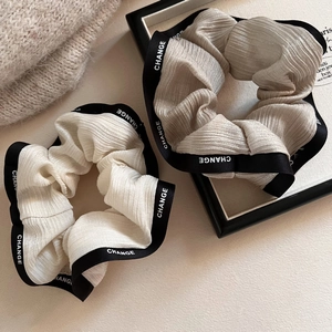 Detailed close-up of cream and champagne ruffled hair scrunchies with black ribbon edges