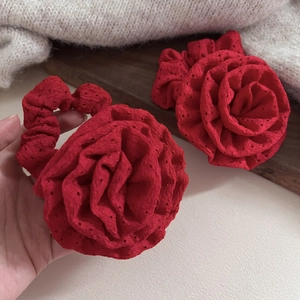 Close-up of vibrant red fabric rose hair ties with intricate 3D layered flower petals