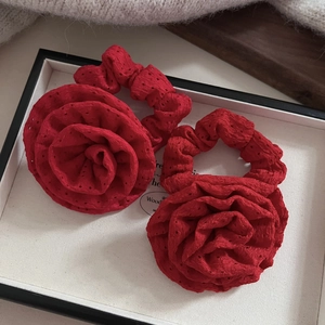 Detail of red fabric rose hair scrunchies with intricate hollow-out texture on a tray