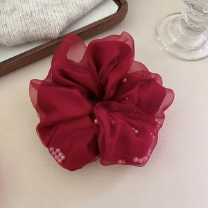 Détail du chouchou en maille rouge foncé avec de délicats ornements en perles