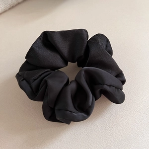 Detail of black satin scrunchie with soft silk texture and subtle bamboo jacquard patterns