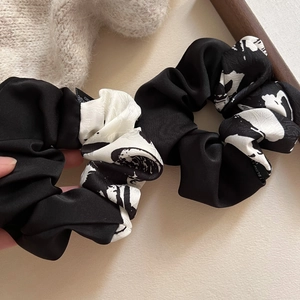 Detail of silk satin scrunchies with ink print, woven labels, and polished texture