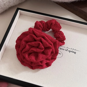 Elegant red fabric rose hair scrunchie with intricate hollow-out texture and soft ruffles