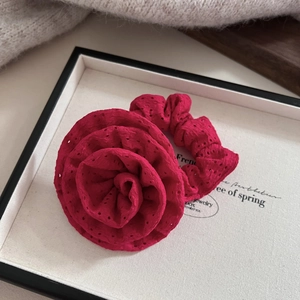 Macro shot of a deep rose red floral scrunchie with eyelet embroidery on a display tray